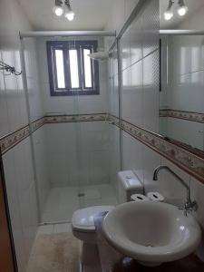 a bathroom with a sink and a shower and a toilet at Apartamento pé na areia 5 pessoas (Beto Carrero). in Penha