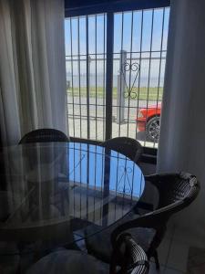 a glass table and chairs with a view of a car at Apartamento pé na areia 5 pessoas (Beto Carrero). in Penha