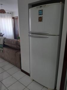 einen weißen Kühlschrank in einer Küche neben einer Couch in der Unterkunft Apartamento pé na areia 5 pessoas (Beto Carrero). in Penha