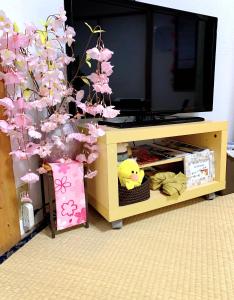 a tv stand with a tree with pink flowers at ヴィラ 奈良 with gift 小さなギフト付 奈良駅から15から20分 in Nara