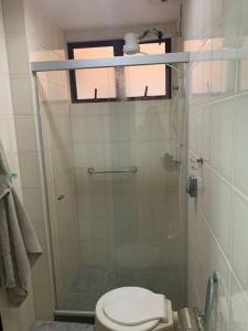 uma casa de banho com um WC e uma cabina de duche em vidro. em Apartamento bem localizado em Cabo Frio