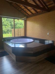 a large tub in a room with a large window at Chalés Estância Campestre in Capitólio