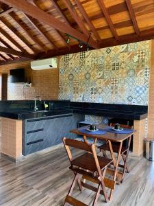 uma cozinha com uma mesa e cadeiras e uma parede de azulejos em Chalés Estância Campestre em Capitólio