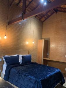 Chalés Estância Campestre في كابيتوليو: غرفة نوم بسرير وملاءات زرقاء واضاءات