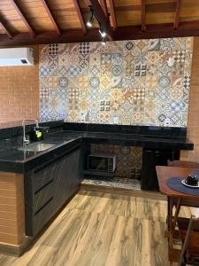 a kitchen with a sink and a tile wall at Chalés Estância Campestre in Capitólio