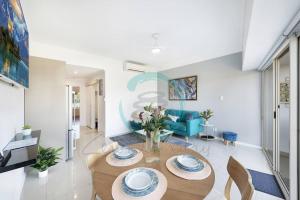 sala de estar con mesa y sofá azul en Zen Marina: 1-BR Executive Apartment By The Bay, en Larrakeyah