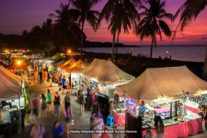 um grupo de pessoas andando em torno de um mercado à noite em Zen Marina: 1-BR Executive Apartment By The Bay em Larrakeyah