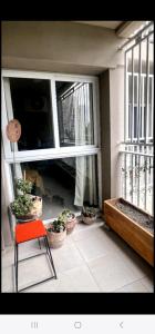 um quarto com vasos de plantas e uma cadeira vermelha numa varanda em Hermoso Departamento en Ciudad de Mendoza em Mendoza
