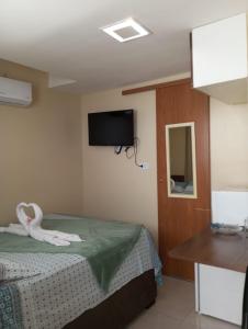1 dormitorio con 1 cama y TV de pantalla plana en Suite 100m da praia de Porto de Galinhas, en Porto de Galinhas