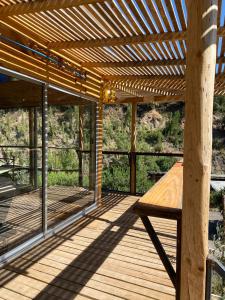 eine Holzterrasse mit einer hölzernen Pergola und einer Bank in der Unterkunft Pobeda del Valle-desconexión-piscina -sauna- 5pax in Guayacán