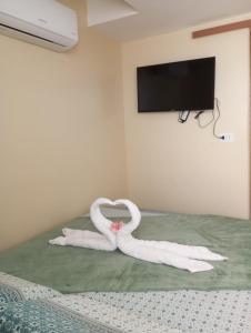 1 cama con 2 toallas en forma de corazón en Suite 100m da praia de Porto de Galinhas, en Porto de Galinhas