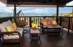 a porch with chairs and tables and a swing at Vacation Getaway in Mango Walk Country Club in Montego Bay