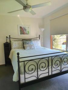sypialnia z łóżkiem z wentylatorem i oknem w obiekcie Beach Garden Getaway w mieście Cheltenham
