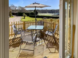 a table and chairs on a deck with an umbrella at Totland in Wootton Bridge