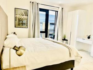 a white bedroom with a bed and a window at Hyde Park Sandton Luxury 2BR Top Floor in Johannesburg +35 photos