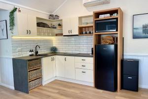een keuken met witte kasten en een zwarte koelkast bij Autumn Beauty - Alpine Cottage 5 in Bright