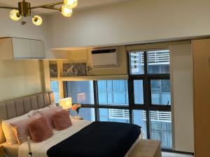 ein Schlafzimmer mit einem Bett und einem großen Fenster in der Unterkunft Viceroy Residences Chic Smart Home wifi Netflix in Manila