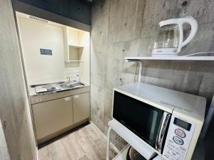 uma pequena cozinha com um micro-ondas e um lavatório em yokohama paradise101 em Yokohama