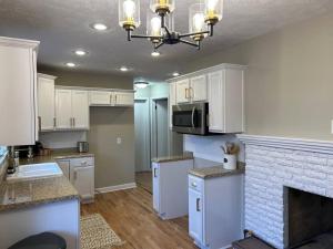 a kitchen with white cabinets and a brick fireplace at Entire Home w/ Free Wi-Fi, Garage, Deck, Yard in Nixa