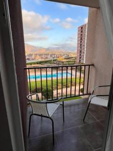 balcón con 2 sillas y vistas a la piscina en Arriendo Depto Diario Alto Hacienda, en Coquimbo