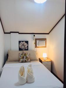 Un dormitorio con una cama con dos zapatos. en Seashells Home, en Panglao