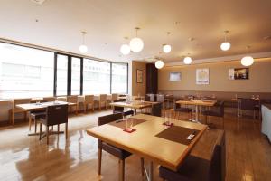 ein Restaurant mit Holztischen und -stühlen und großen Fenstern in der Unterkunft Okayama View Hotel in Okayama