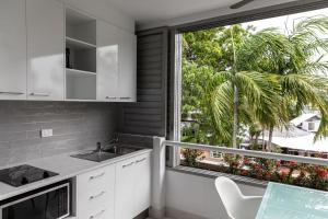een keuken met witte kasten en een groot raam bij Club Tropical Resort with Onsite Reception & Check In in Port Douglas