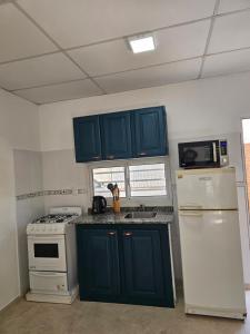 een keuken met blauwe kasten en een witte koelkast bij Pringles Dpto Temporario 2 in Formosa