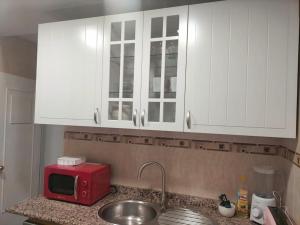 cocina con armarios blancos y microondas rojo en Porthos, bonito apartamento zona Puerta del Ángel en Madrid