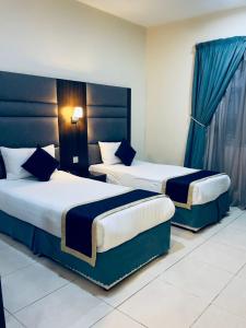 duas camas num quarto de hotel com cortinas azuis em شقق عنوان المدينة للوحدات السكنية em Al Madinah
