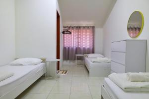 Habitación blanca con 2 camas y espejo. en Adno Homestay#4BR#12 Single 2 Sb#High Speed Wifi#14pax, en Simpang Ampat