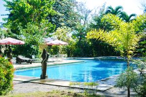 a swimming pool with a statue in the middle at Votel Manyar Resort Banyuwangi in Ketapang