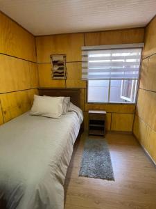 ein kleines Schlafzimmer mit einem Bett und einem Fenster in der Unterkunft Acogedora casa céntrica en Panguipulli in Panguipulli