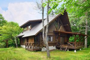 a log cabin in the woods with trees at Rental Log Urube Village in Tsumagoi