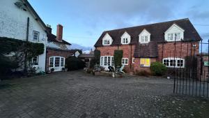 a large brick house with white windows and a driveway at Holly Cottage in Muxton