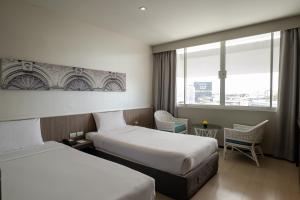 a hotel room with two beds and a window at Pearl Hotel - SHA Plus in Phuket