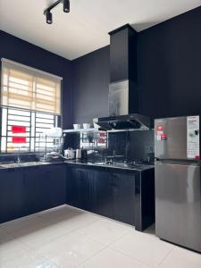 cocina con paredes azules y electrodomésticos de acero inoxidable en Calma Villa @ Pendang, en Pendang