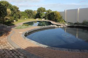 a swimming pool with a brick pathway around it at The Potting Shed Self Catering in Hermanus