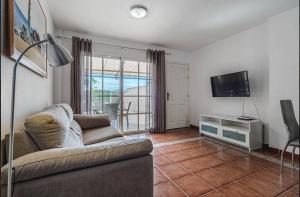 een woonkamer met een bank en een flatscreen-tv bij Comfy Duplex For Family Vacations in Callao Salvaje