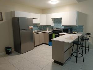 a kitchen with a refrigerator and some bar stools at Lovely 2 BedRoom c̅ Netflix across National Stadium Kingston in Kingston