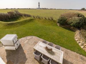 a wooden bench sitting on a patio with a lighthouse in the background at Leuchtturmblick Süd von Appartements & Mehr in Kampen