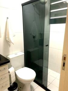 a bathroom with a toilet and a glass shower at Apto Centro Wifi Shopping Garage in Taubaté