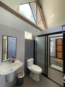 EPBliss Villas Resort Siargao في جنرال لونا: حمام به مرحاض أبيض ومغسلة