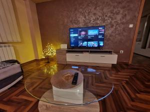 un soggiorno con TV e tavolo in vetro di Dunja ambient a Kraljevo