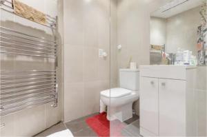 y baño blanco con aseo y ducha. en Chic DuoRooms with Modern Comfort for Families, en Kent