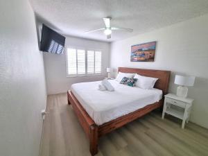 um quarto com uma cama com lençóis brancos e uma televisão em The Poplars, Pool Access Getaway em Nelson Bay