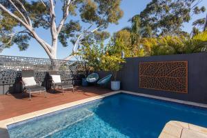 Stella Retreat - Townhouse with pool في East Fremantle: فناء به مسبح وكراسي بجوار سياج