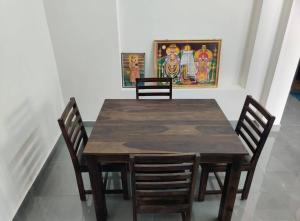 a wooden table with four chairs and a painting on the wall at Wind Chimes in Tiruvannāmalai +20 photos