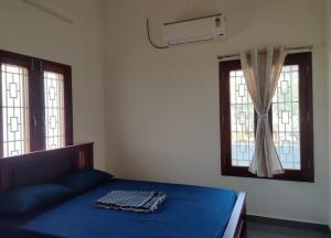 1 dormitorio con 1 cama azul y 2 ventanas en Wind Chimes, en Tiruvannāmalai