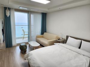 a bedroom with a bed and a couch and a window at Sokcho Summitbay 1704 "Ocean View" in Sokcho